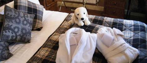 A neatly made bed with a plaid blanket, two pillows, and a white dog toy.