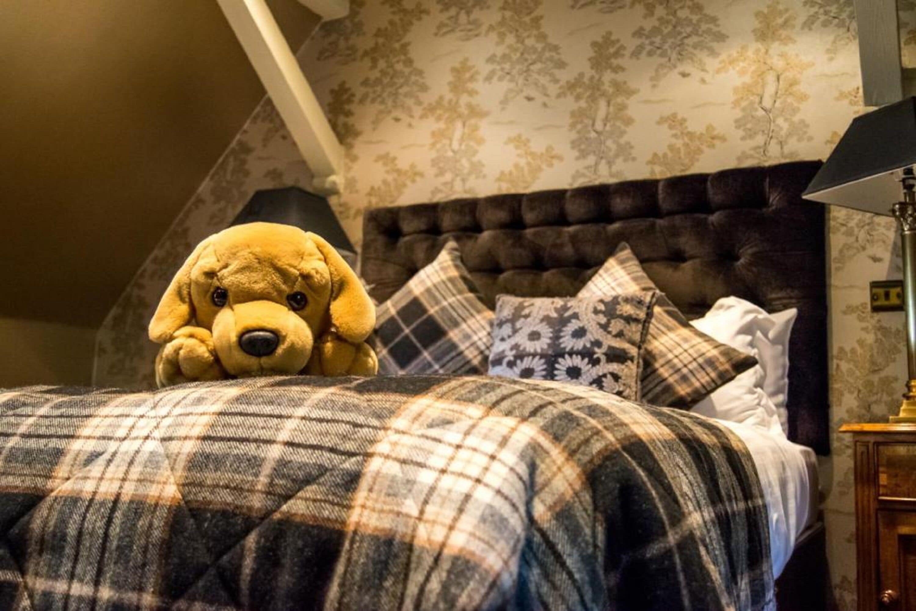 A bedroom with a large bed, a plush dog toy, and patterned pillows.