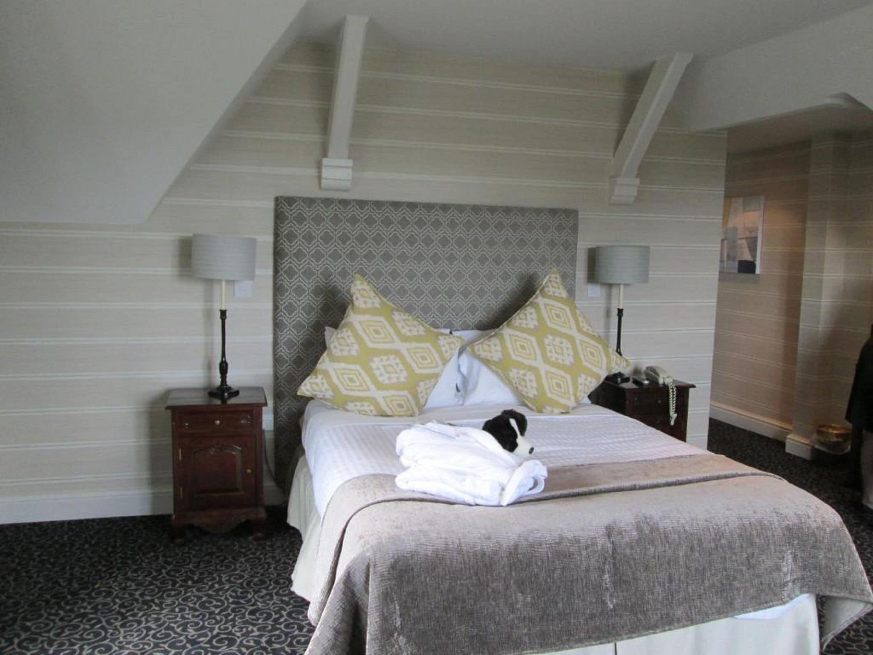 A hotel room with a large bed, two bedside tables, a nightstand, and a patterned carpet.