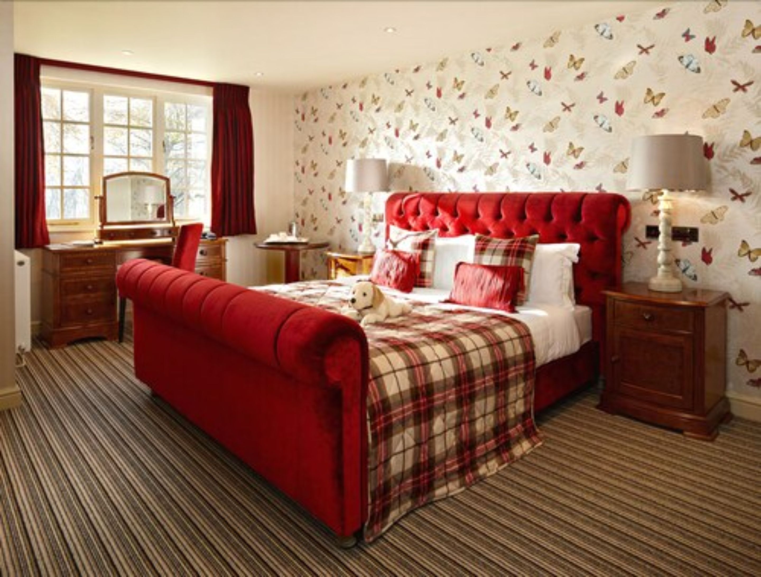 A bedroom with a large bed, a dresser, a desk, and a mirror.