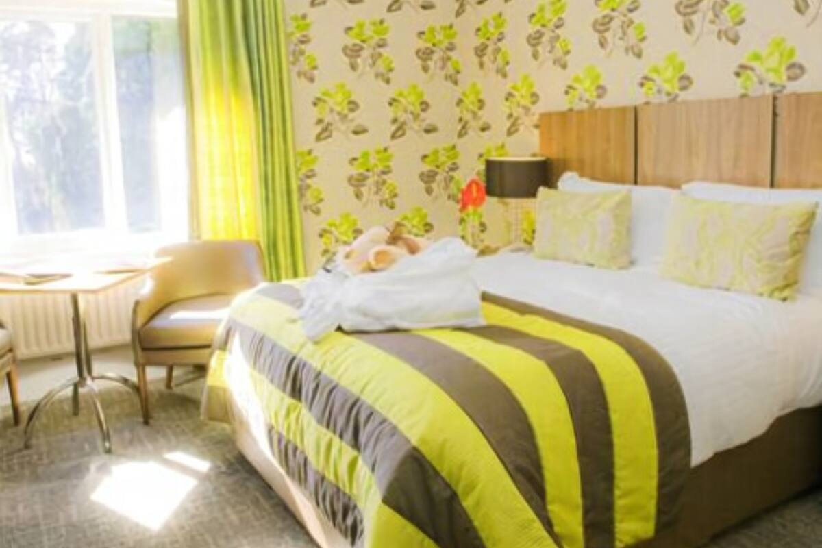 A hotel room with a bed, a chair, a table, and a window with curtains.