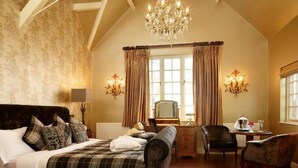 Ein geräumiges Schlafzimmer mit einem großen Bett, einer Kristallleuchtre und einem Schreibtisch mit Stuhl.