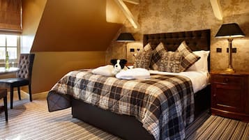 A bedroom with a large bed, two bedside lamps, a chair, and a desk.