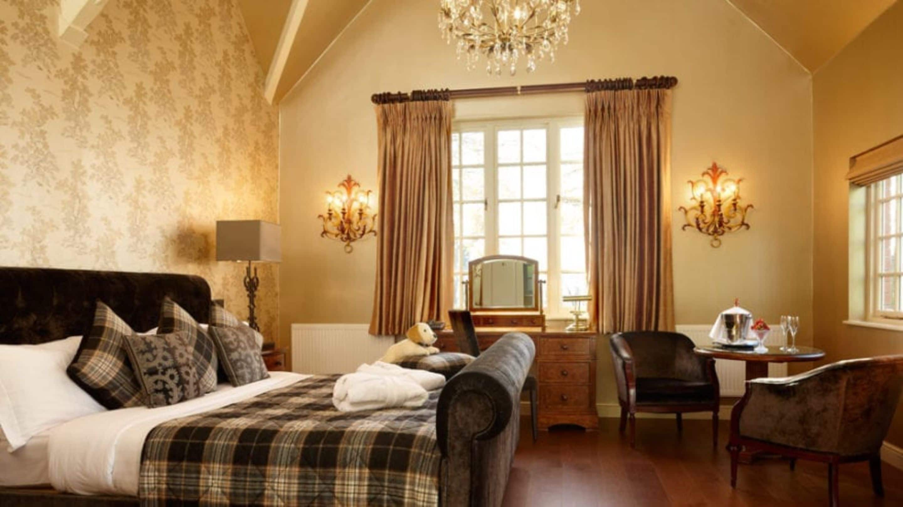 A bedroom with a bed, a dresser, a desk, a chair, and a chandelier.