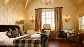 A bedroom with a bed, a dresser, a desk, a chair, and a chandelier.