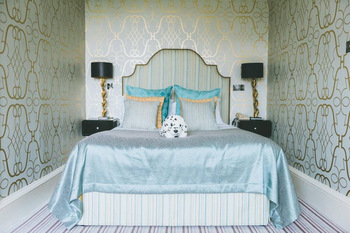 A bedroom with a striped bedspread, a patterned headboard, and two bedside lamps.