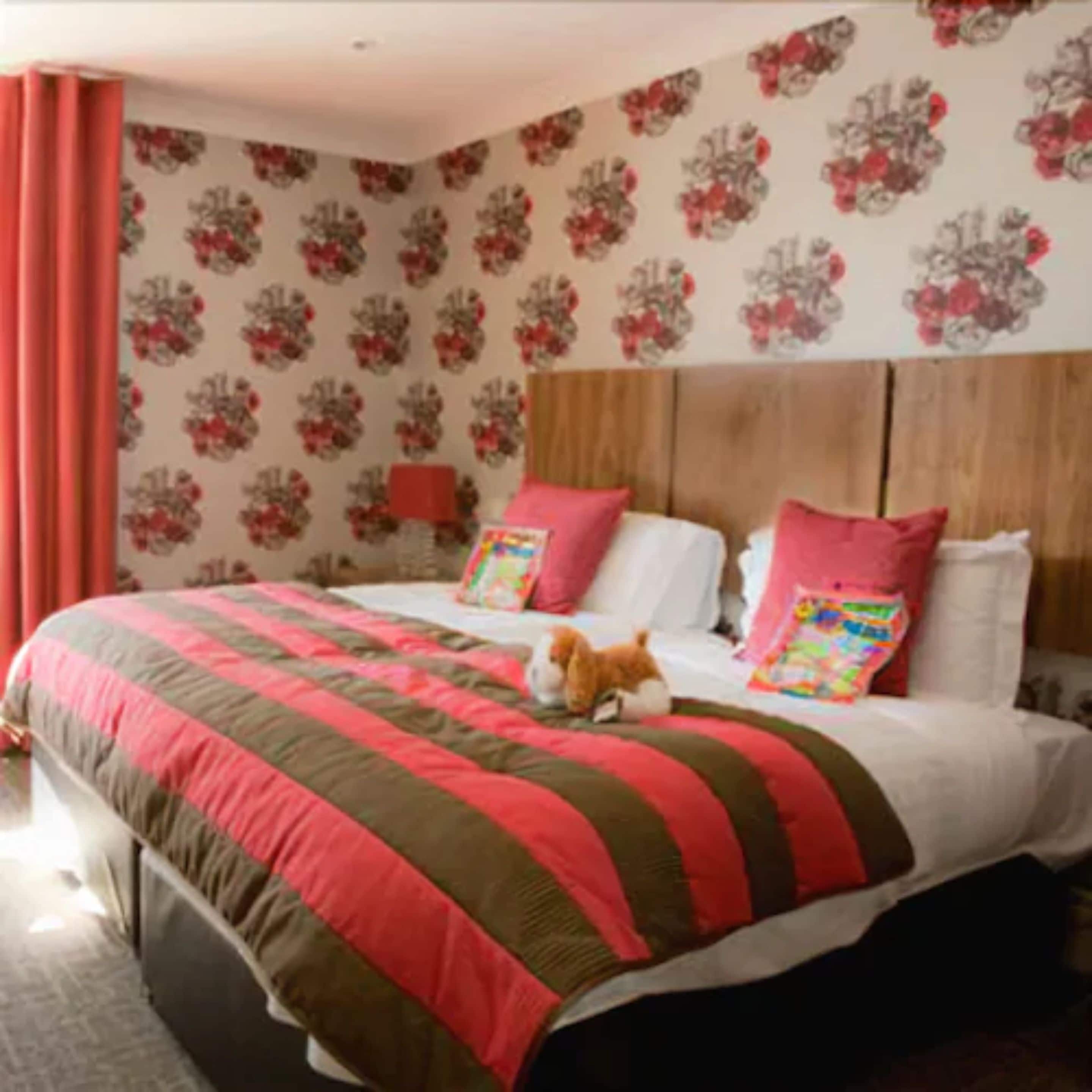 A bedroom with a large bed, two pillows, and a teddy bear.