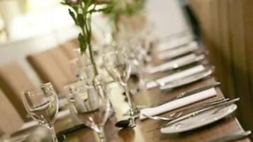 A long dining table set with multiple place settings, including plates, cutlery, and glasses.