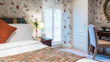 Un dormitorio con una cama, una mesita de noche, una silla y una puerta decorada con estampado de mariposas.