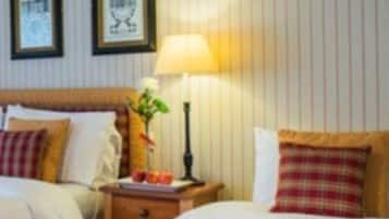 A hotel room with two beds, a nightstand with a lamp, and framed pictures on the wall.