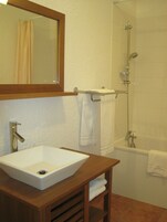 Un baño con lavamanos blanco, espejo, ducha y bañera.