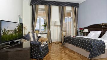 Een hotelkamer met een bed, een televisie, een stoel en gordijnen.