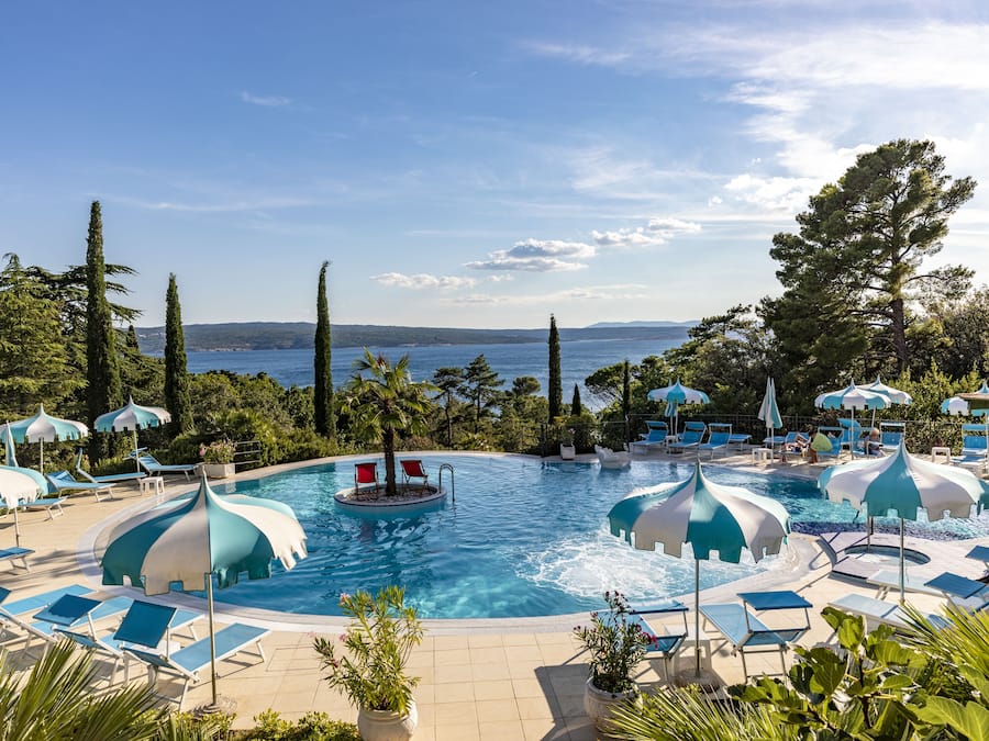 Una piscina cubierta, una piscina al aire libre, sombrillas, tumbonas