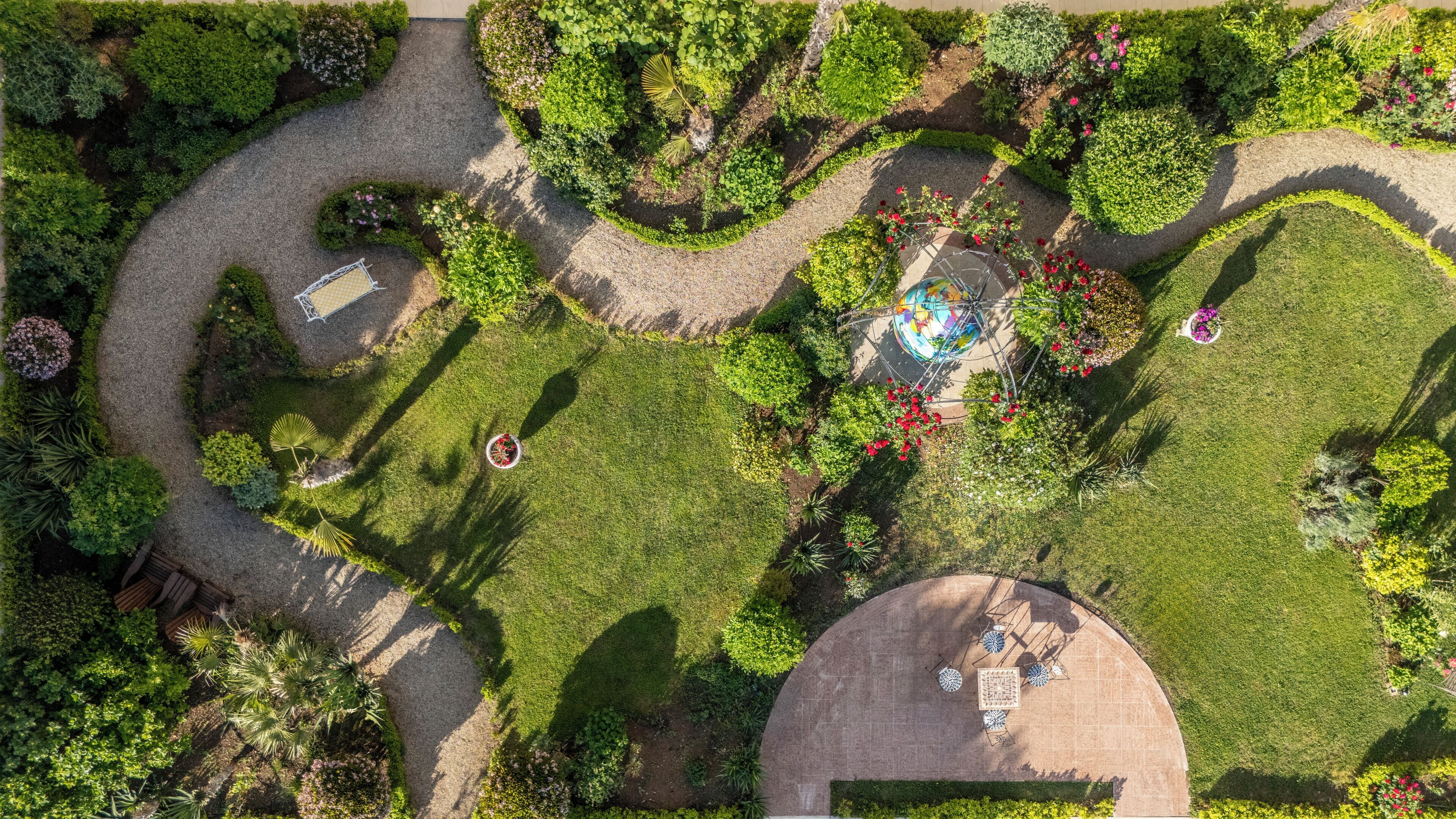 An aerial view of a landscaped garden with a circular seating area and a gazebo.