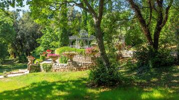 A garden with a gazebo, stone walls, and various plants.