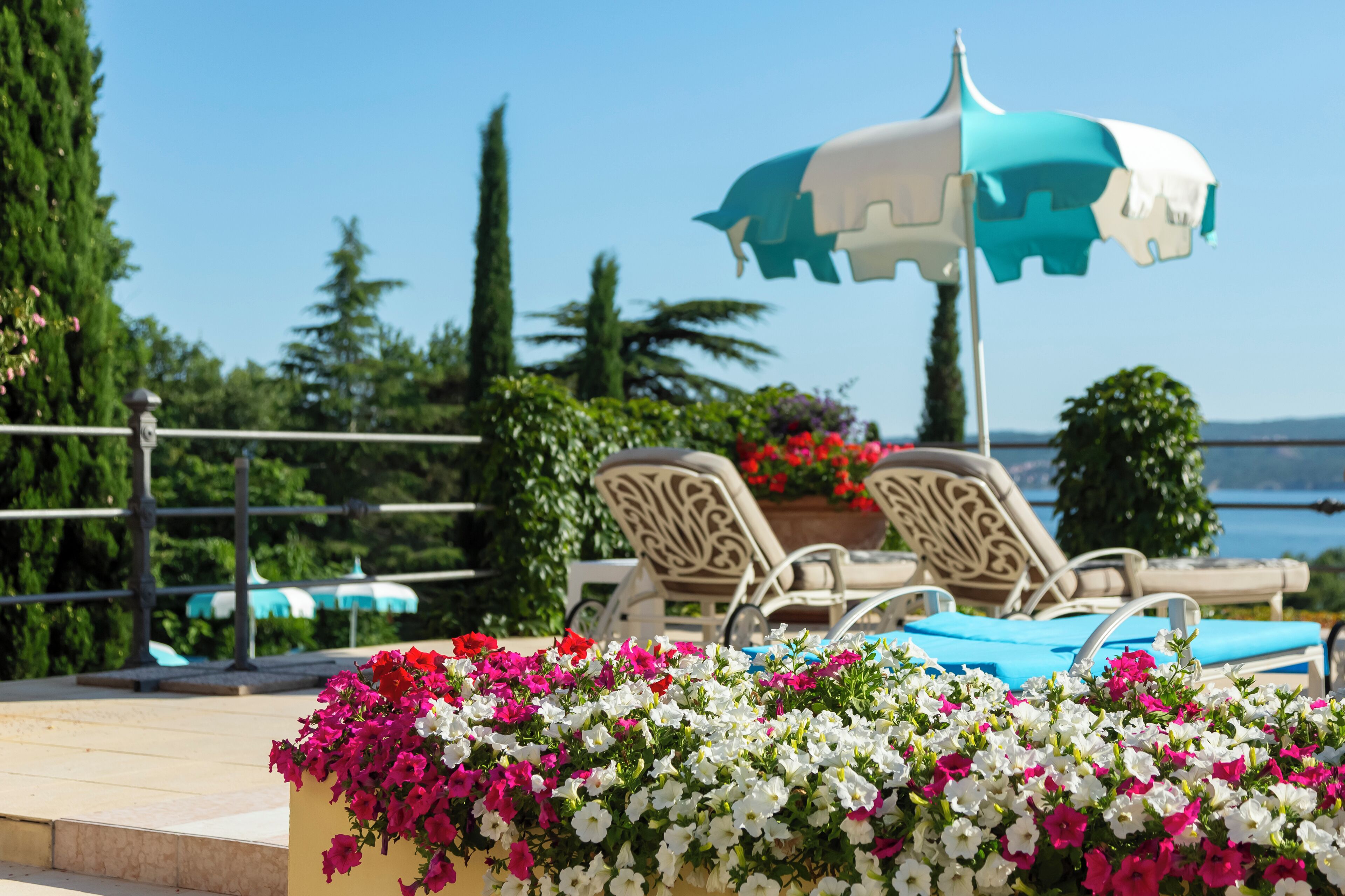 A poolside area with lounge chairs, a decorative umbrella, and a flower arrangement.