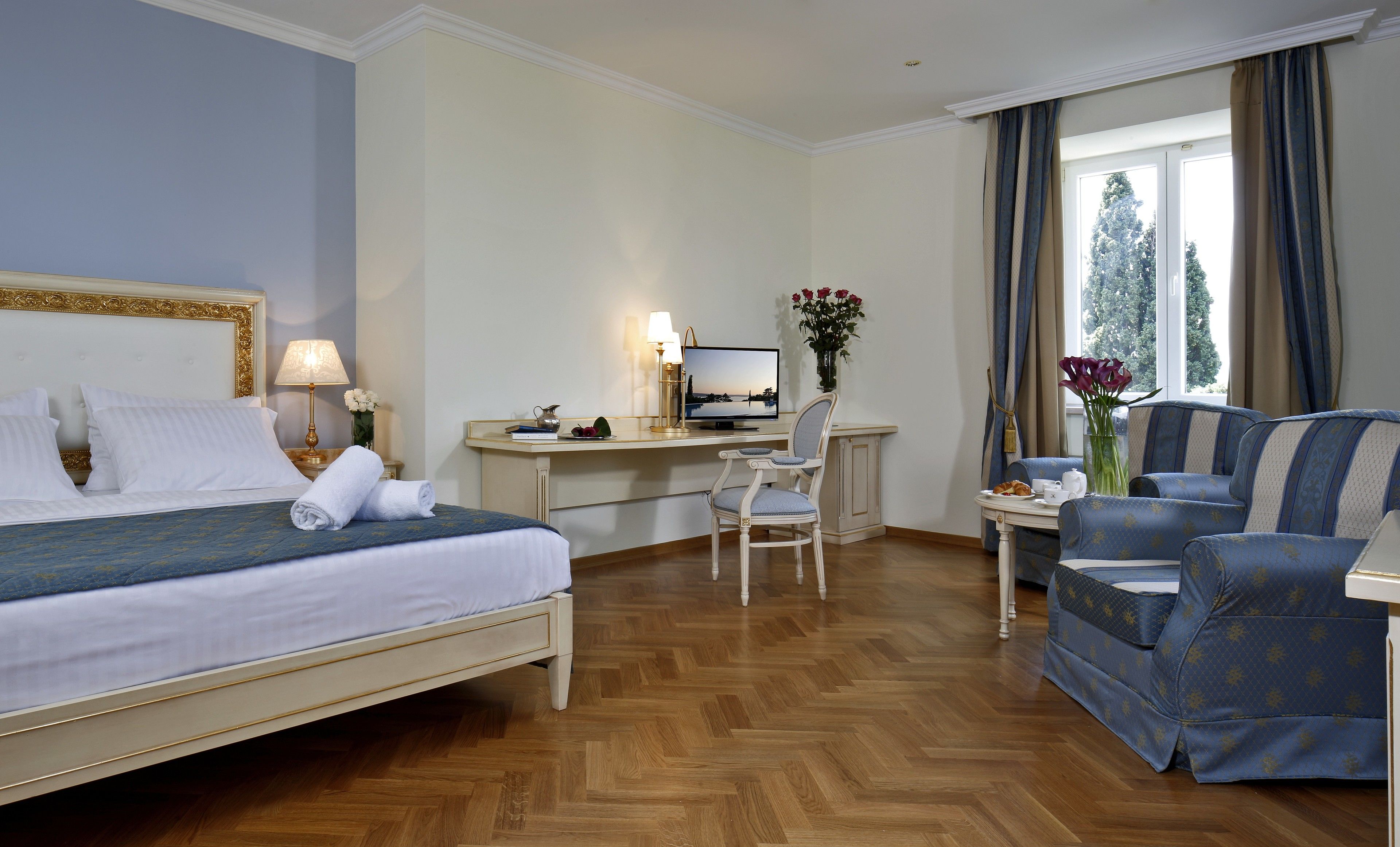 A hotel room with a bed, desk, chair, and a sofa.