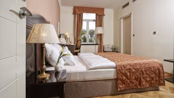 A neatly arranged bedroom with a bed, bedside tables, lamps, and a window with curtains.