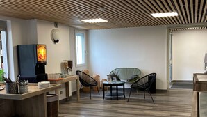 Un intérieur moderne avec un plafond en bois, un téléviseur à écran plat, un coin cuisine et un espace détente avec des chaises et un canapé.