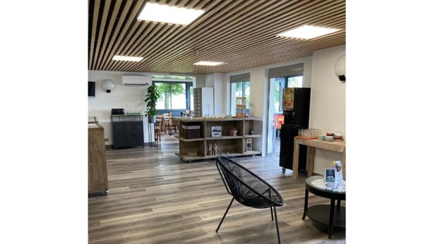 Une pièce spacieuse avec un plancher en bois, une chaise noire, une petite table et un comptoir où sont disposés divers objets.