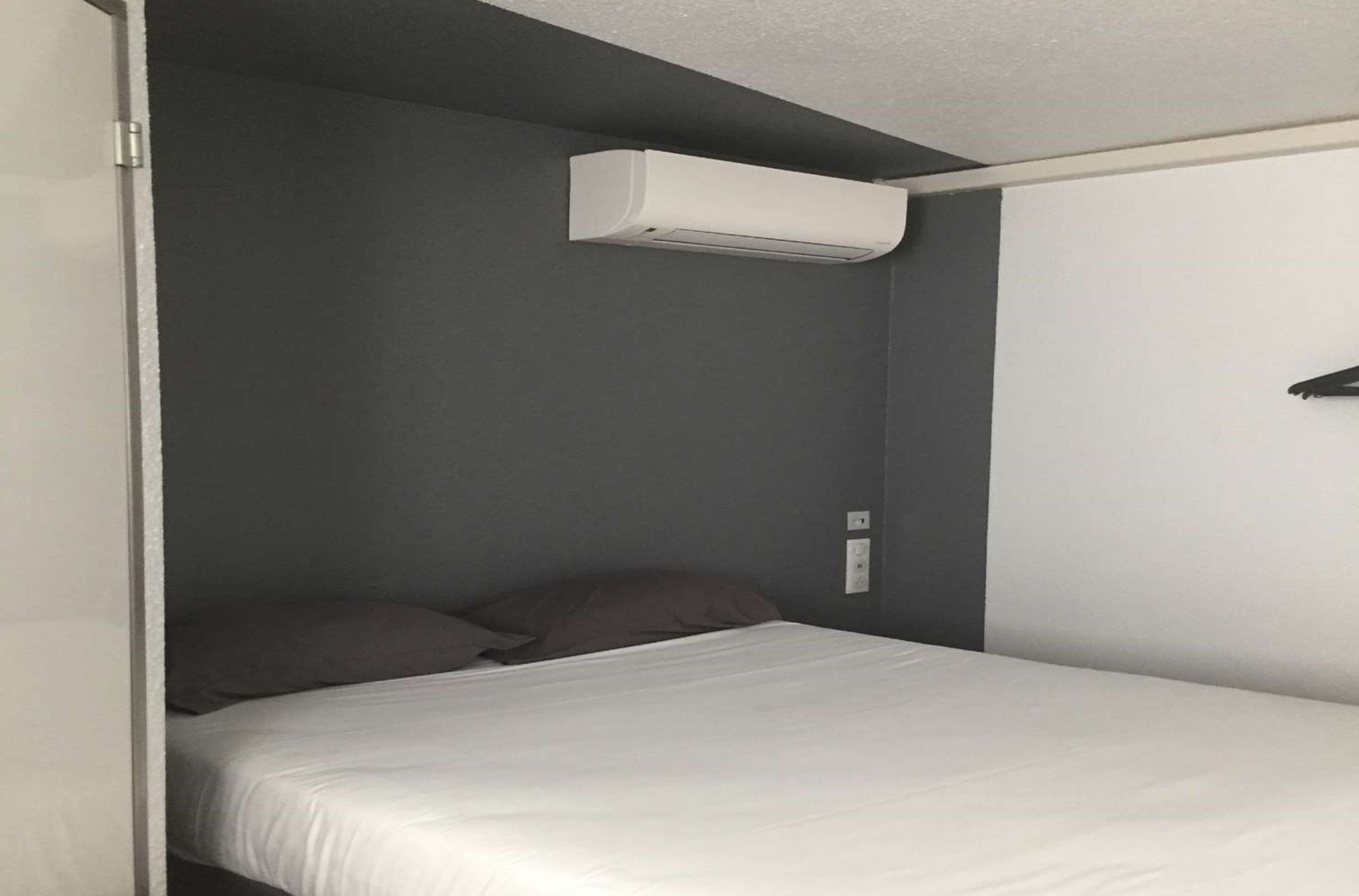 A single bed with a white mattress and dark wall.