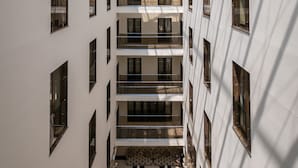 Useita tasoja sisältävä avoin aula, jonka lasikatto päästää luonnonvaloa sisään ja valaisee tilan.