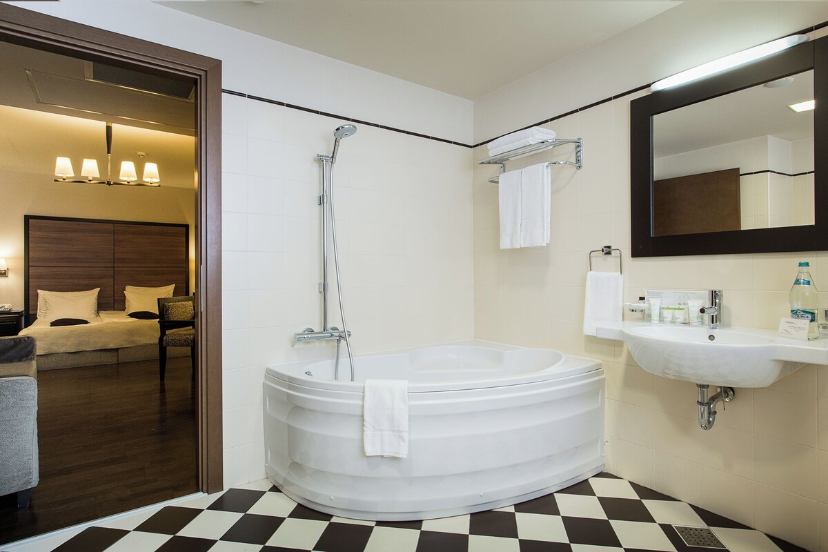 A modern bathroom with a large bathtub, a sink, and a mirror.