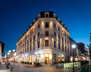 A multi-story hotel with a classic architectural style, featuring a central entrance with a canopy, multiple balconies, and a well-lit facade. - Dor Bucharest, Curio Collection by Hilton (Bucharest)