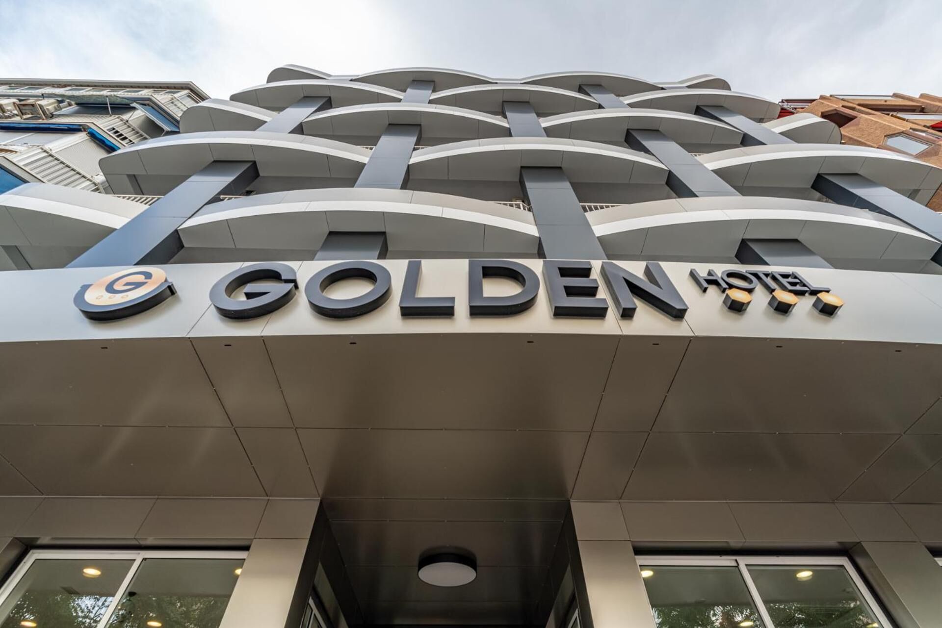 Fachada del Hotel Golden, con un diseño arquitectónico moderno que presenta líneas curvas y un letrero destacado.