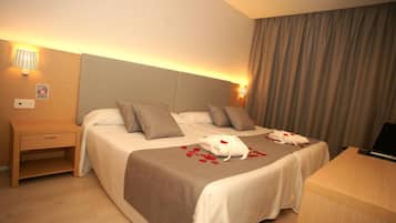 Una habitación de hotel con cama, mesitas de noche, un escritorio y una lámpara.