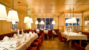 Un restaurante con paredes de paneles de madera, manteles blancos y sillas rojas.