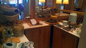 A breakfast buffet setup with wicker baskets, a coffee station, and a newspaper spread.