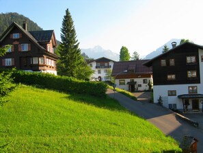 A row of traditional European-style buildings with sloped roofs, set against a backdrop of mountains. - Riezler Hof (Mittelberg)