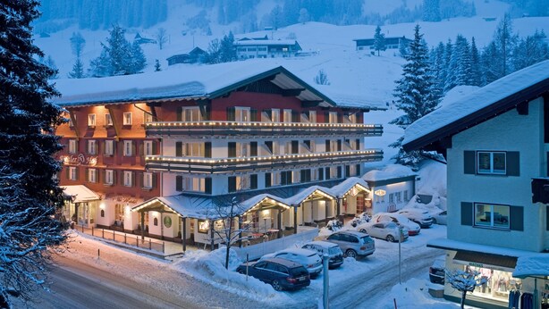 A hotel with multiple buildings, a snow-covered landscape, and parked cars.