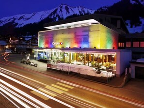 A modern building with a colorful facade, a casino sign, and a restaurant with outdoor seating. - Riezler Hof (Mittelberg)