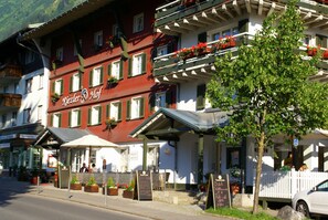 A hotel with a red facade, multiple balconies with flower boxes, and outdoor seating areas. - Riezler Hof (Mittelberg)