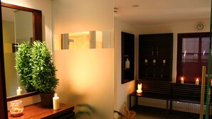 Habitación de hotel con tocador de madera, una planta en maceta, dos velas encendidas y un espejo que refleja la habitación.
