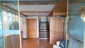Un interior de madera con una escalera, un sofá y un separador de vidrio.