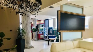 Un salón amplio con un sofá beige grande, una araña y una mesa de fútbol.