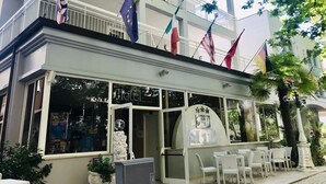 Un hotel con balcón, varias banderas y mobiliario exterior.