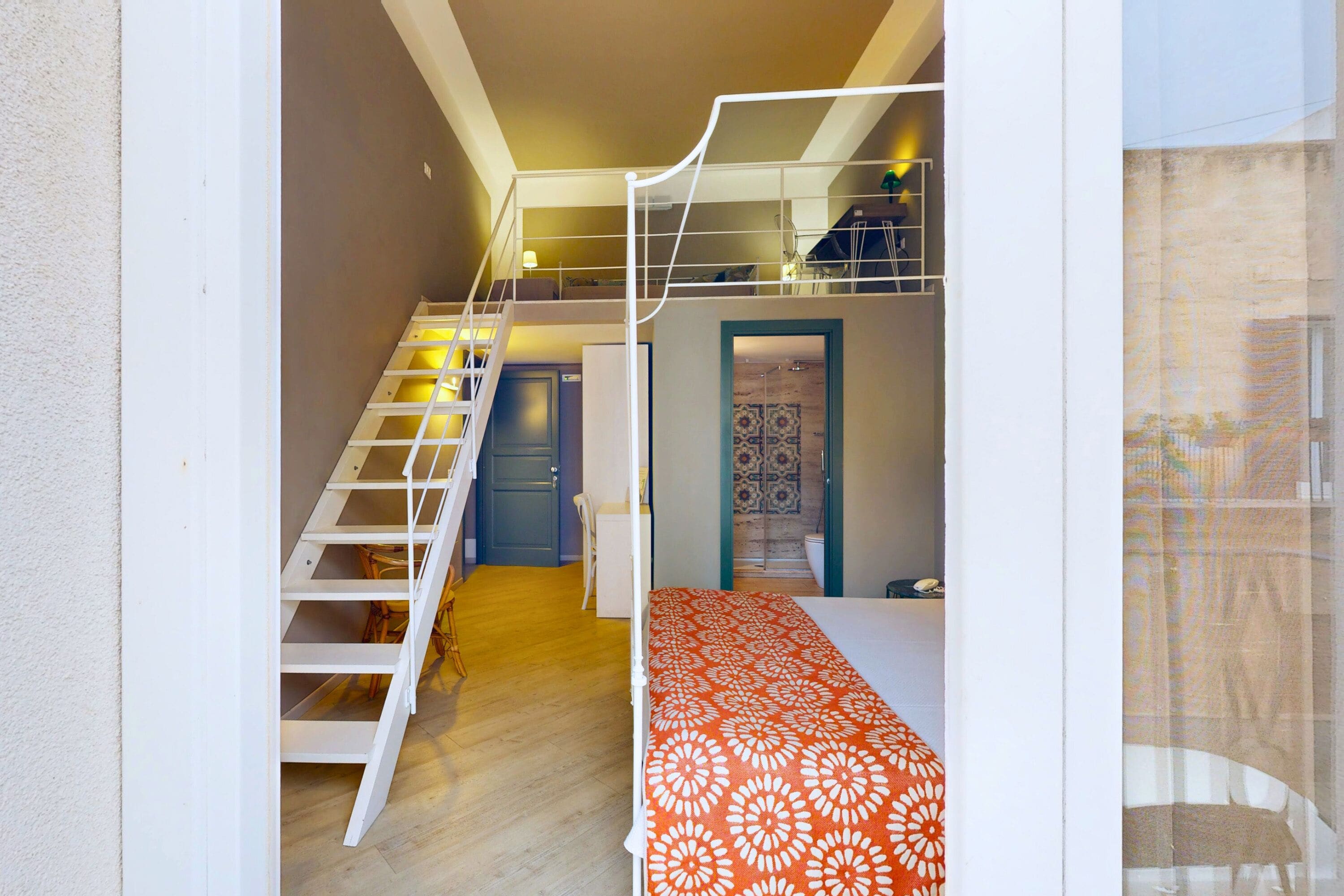 A room with a bunk bed, a staircase, and a door leading to another room.