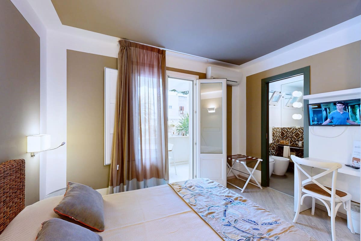 Una habitación de hotel con una cama, televisión, escritorio y silla.