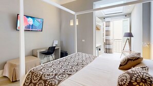 A modern hotel room with a bed, a desk, a chair, and a television.