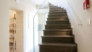 A modern staircase with glass railings and a fire alarm on the wall.