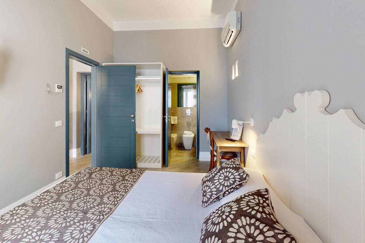 Un dormitorio con cama, almohadas, escritorio y una silla.