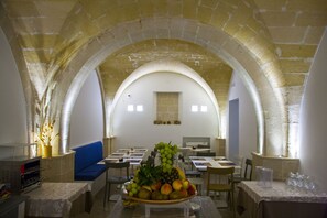 A dining area with tables, chairs, and a fruit bowl on a table. - Aegusa (Favignana)