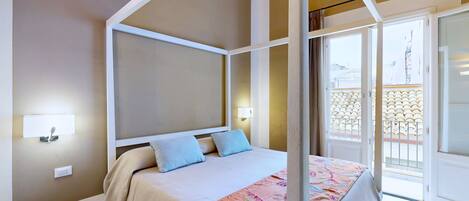 A bedroom with a four-poster bed, a bedside table, and a view of the outside balcony.