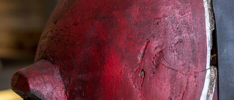 A close-up of a red, weathered object with a pointed end and a circular detail on its side.