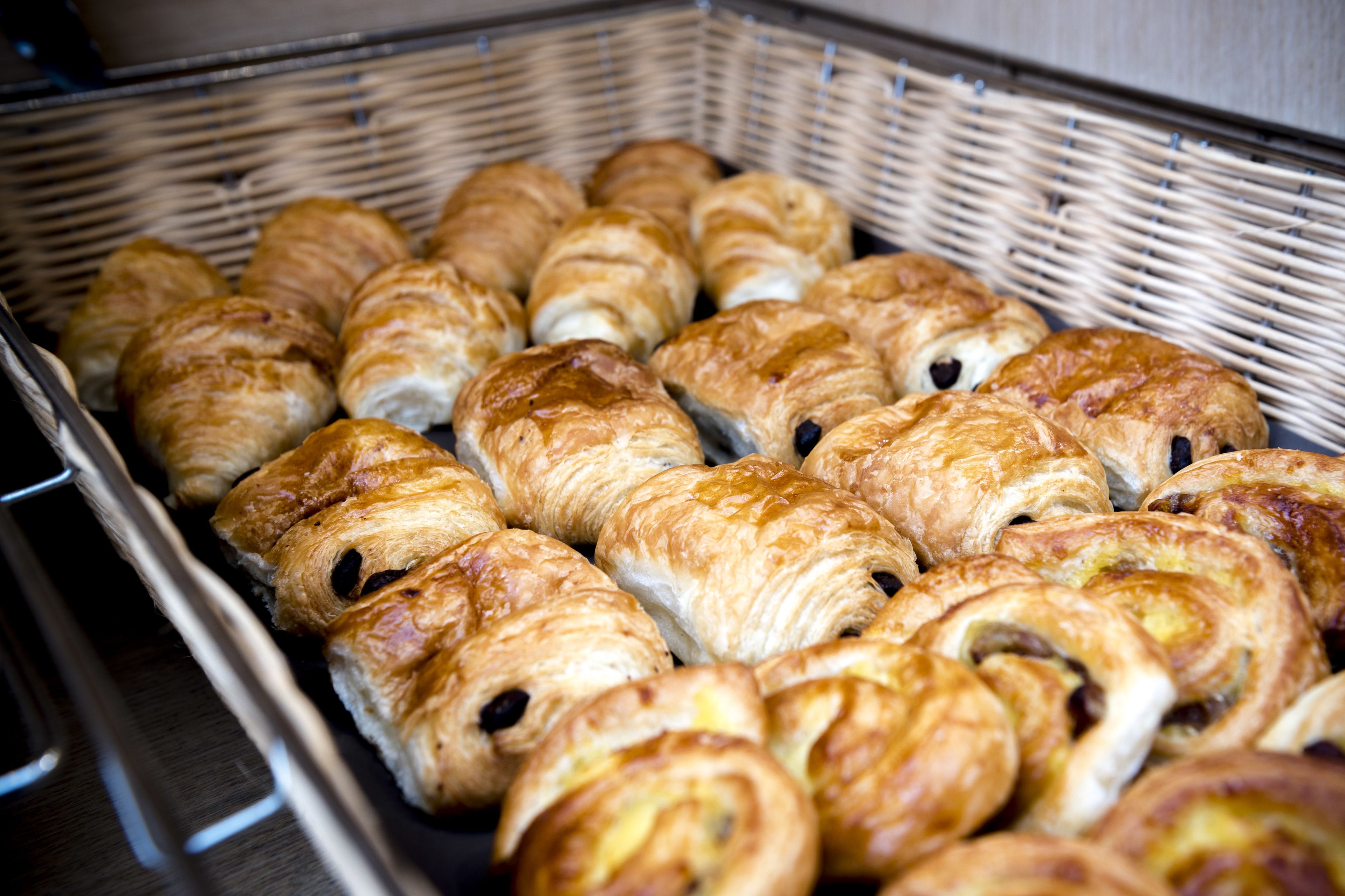 A basket filled with various types of pastries, including croissants and other baked goods.