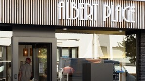 A red vintage car parked in front of a building with a sign that reads "ALBERT PLACE". - Hotel Albert Plage (Knokke-Heist)